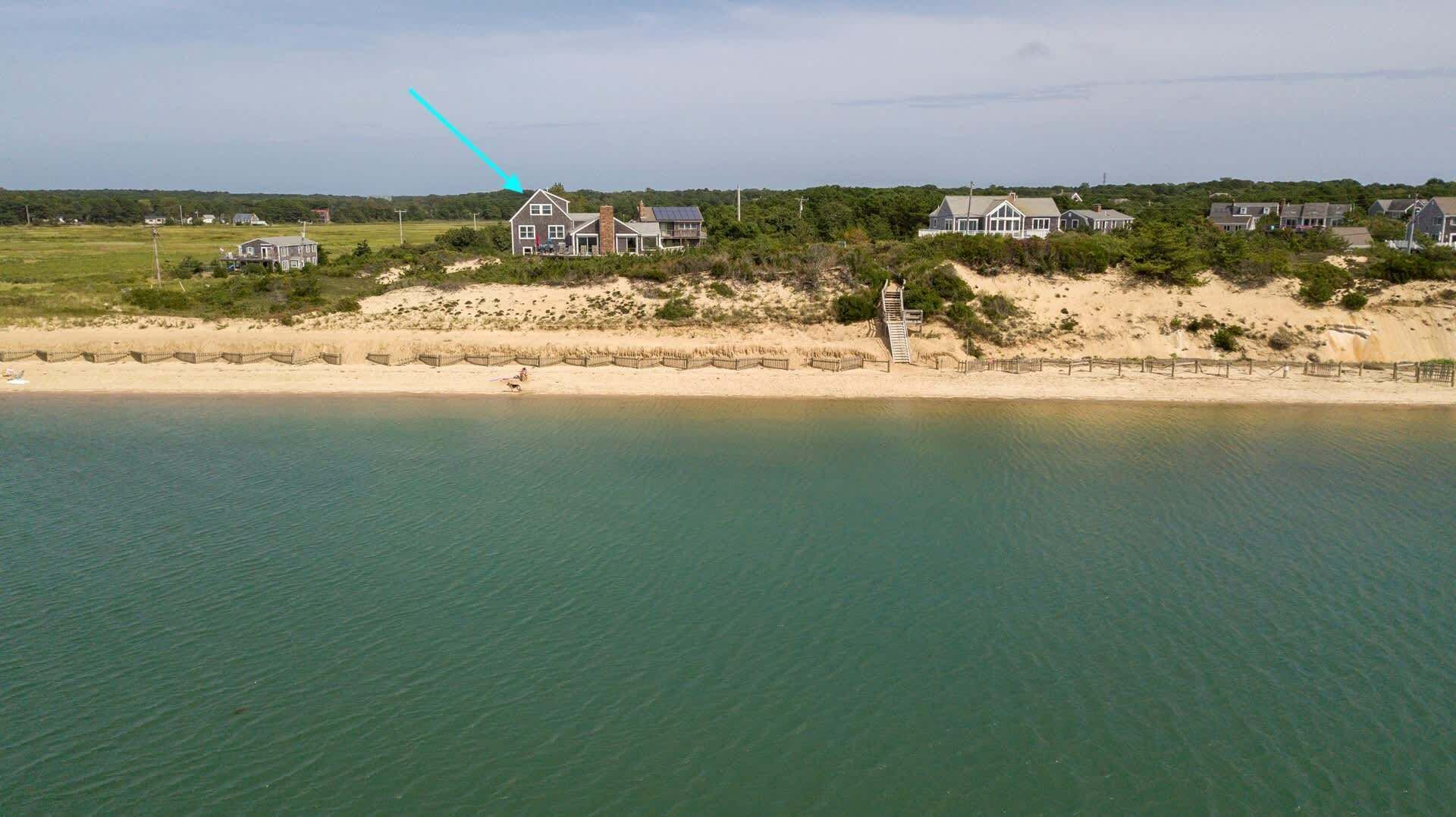 A coastal property with a sandy beach, a wooden fence, and a clear view of the ocean.