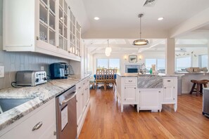 A spacious kitchen with white cabinetry, a marble countertop, and a central island.