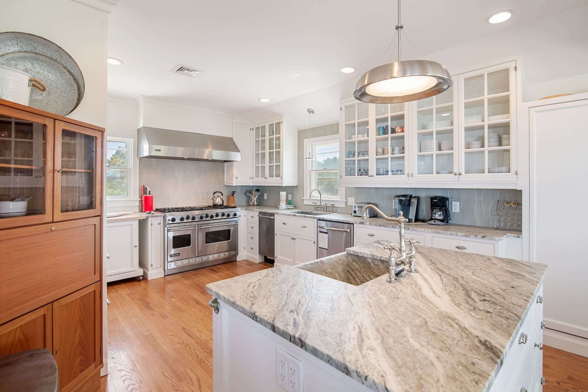 A modern kitchen with white cabinetry, stainless steel appliances, and a marble countertop.