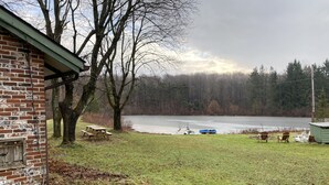 Une propriété au bord du lac, avec un bâtiment en briques, une table de pique-nique et un quai.