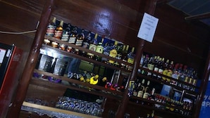 A bar area with shelves stocked with various liquor bottles and glasses.