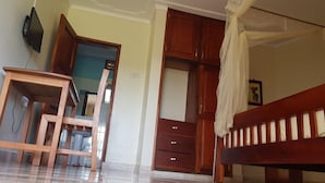 A room with a wooden desk, a bed with a canopy, and a wardrobe.