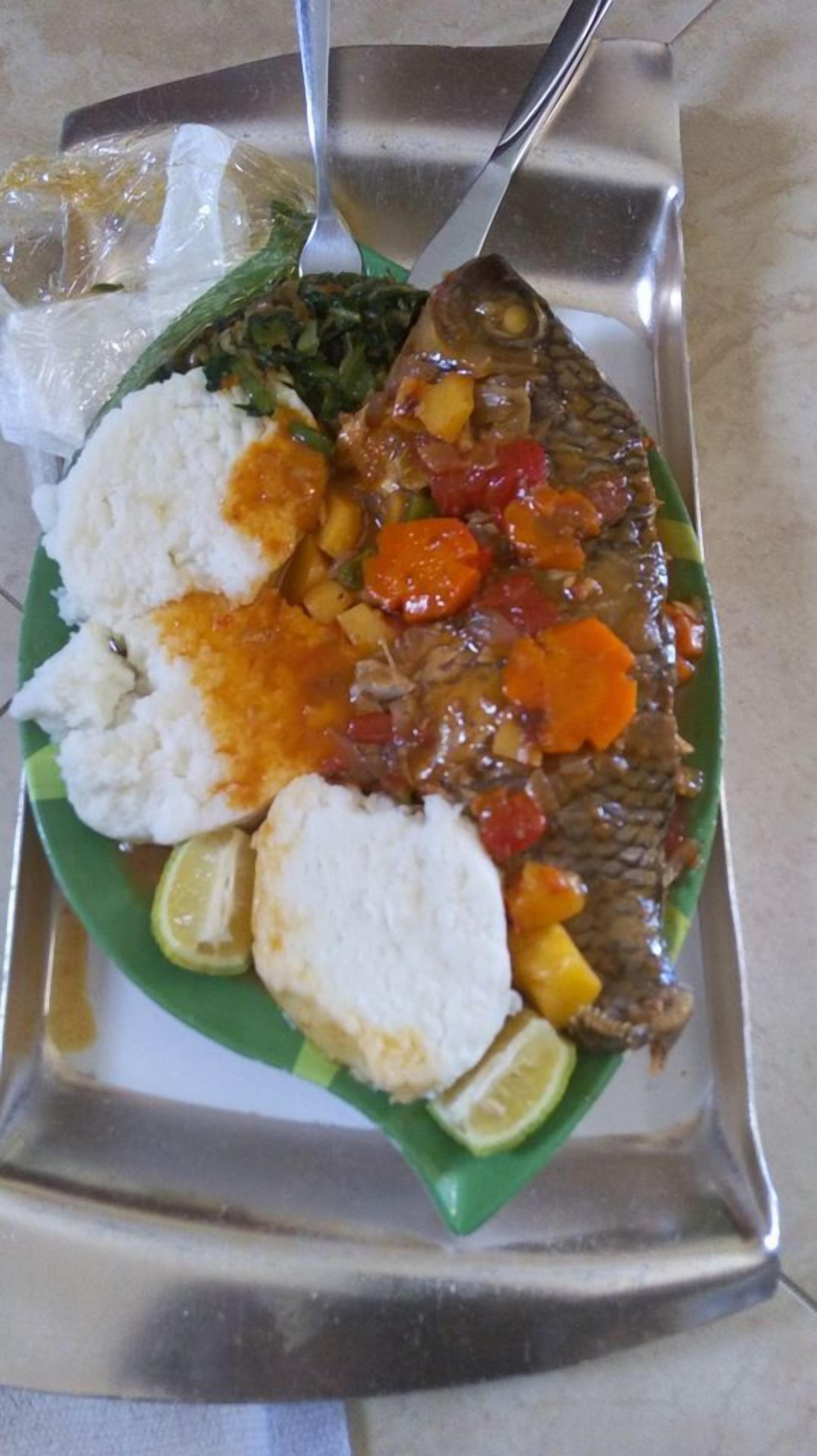 A plate with fish, rice, and vegetables on a tray.