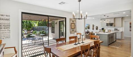 A modern kitchen with a central island, wooden dining table, and chairs.