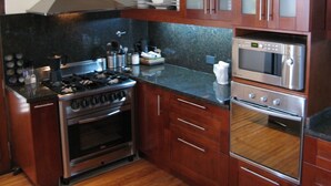 Une cuisine avec des meubles de rangement en bois, une cuisinière à gaz, un four et un four à micro-ondes.