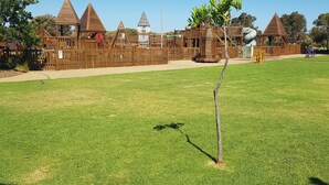 Ein Spielplatz mit Holzspielgeräten und einem eingezäunten Bereich.