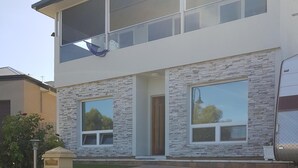 Ein modernes, zweistöckiges Haus mit einer Steinaußenwand, großen Fenstern und einem gepflasterten Auffahrt.