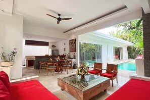 Ein modernes Wohnzimmer mit einem Glastisch, roten Sofas und einem Essbereich mit Holzkästen.