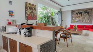 Een moderne keuken met een centraal eiland, een eethoek met stoelen en een rode bank.