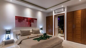 Een moderne slaapkamer met een groot bed, een nachtkastje, een wandairconditioner en houten kasten.