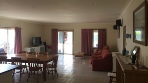 A spacious living area with a dining table, chairs, a sofa, and a television. - Lane-way Holiday Rental -3 Minutes walk from the beach (Moonta Bay)