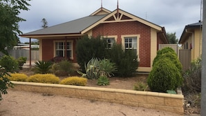 A single-story house with a red brick exterior and a gabled roof. - Lane-way Holiday Rental -3 Minutes walk from the beach (Moonta Bay)