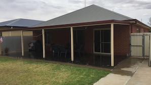 A house with a covered patio, a garage, and a fenced backyard. - Lane-way Holiday Rental -3 Minutes walk from the beach (Moonta Bay)