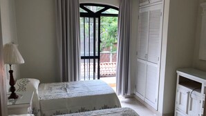 A hotel room with two beds, a nightstand, a lamp, a wardrobe, and a view of the outside. - HERMOSA CASA EN AJIJIC (San Antonio Tlayacapan)