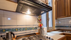A kitchen with a gas stove, stainless steel appliances, and wooden cabinets. - Piazza Navona Charming Apartment (Roma)