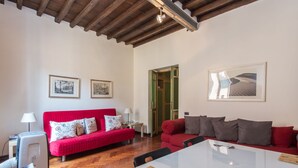 A spacious living area with a red sofa, a white table, and a wooden ceiling. - Piazza Navona Charming Apartment (Roma)