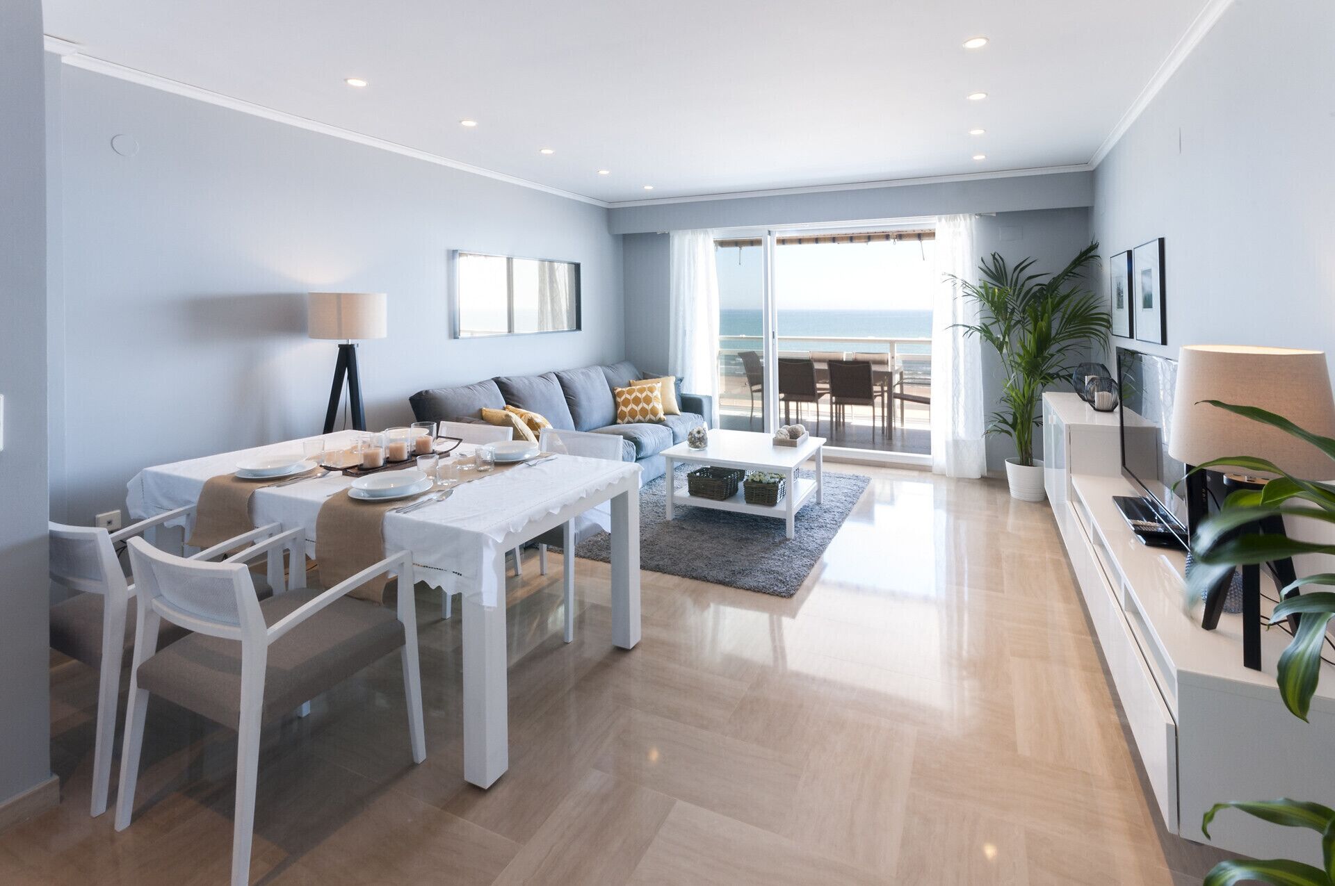A modern living room with a dining area, a sofa, a coffee table, and a TV.