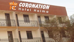Ein mehrgeschossiges Hotel namens „Coronation Hotel Hoima“ mit Balkonen und Fenstern.