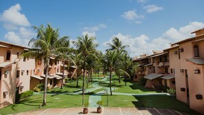 Un resort con edificios de varios pisos, palmeras y un césped bien cuidado.