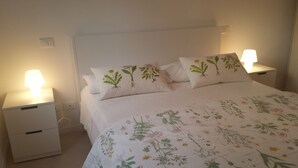 A bedroom with a bed, two bedside tables, and a nightstand.