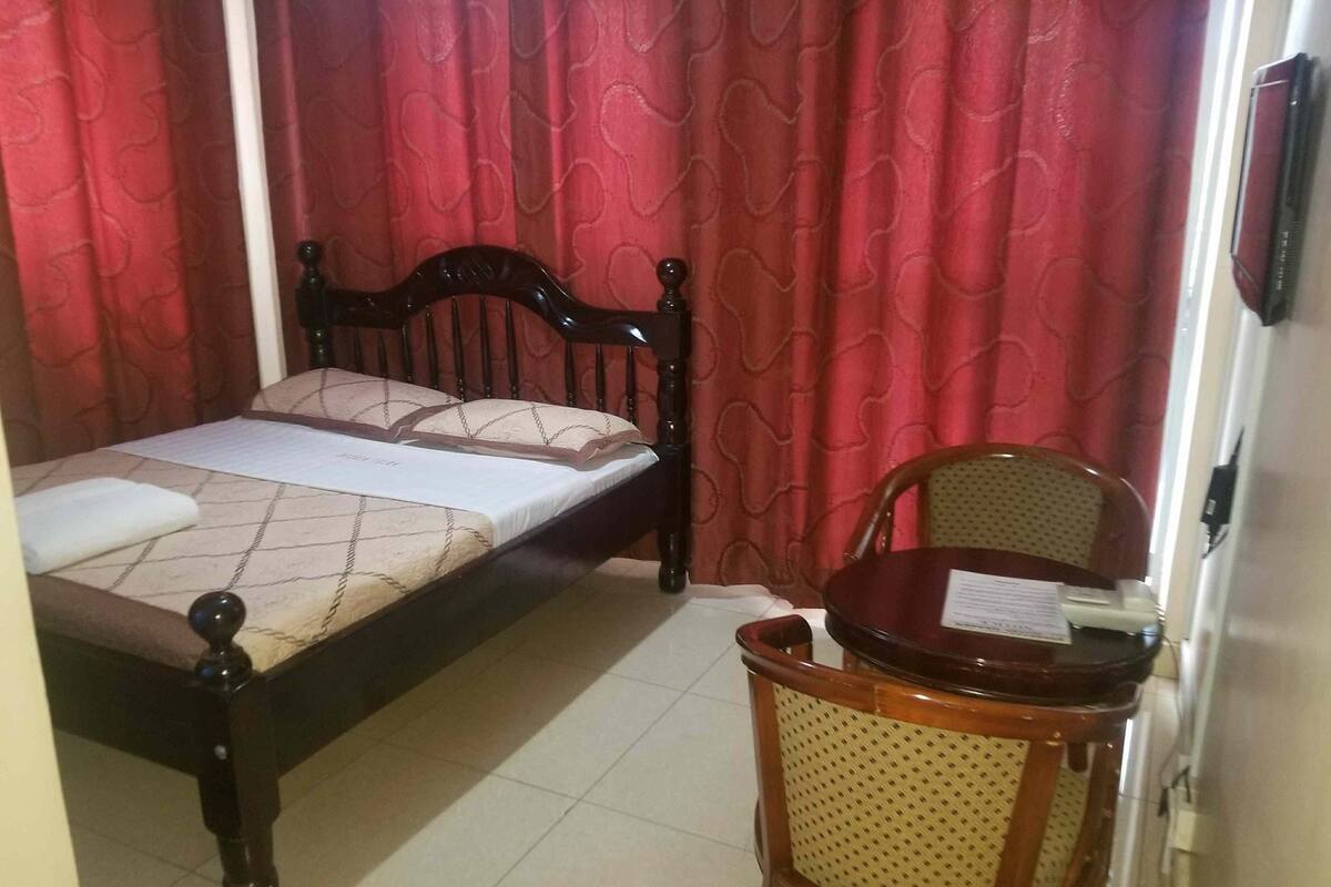 A small, neatly arranged bedroom with a single bed, a chair, and a table.