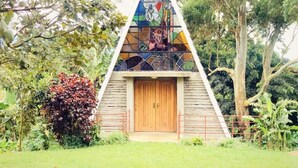 Un bâtiment triangulaire avec une porte en bois et un vitrail aux couleurs vives.