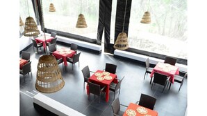 Un restaurant avec de nombreuses tables et chaises, dont certaines sont recouvertes de nappes rouges et agrémentées de sets de table en forme d’étoile.