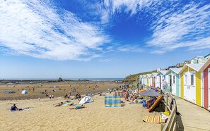 A beach with colorful beach huts, tents, and people relaxing on the sand. - Family & Pet Friendly Chalet - sleeps 5
 (Kilkhampton)