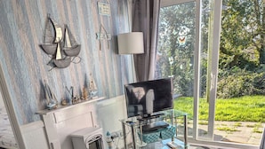 Una sala de estar moderna con un sofá, una chimenea, un televisor y una mesa de centro de vidrio.