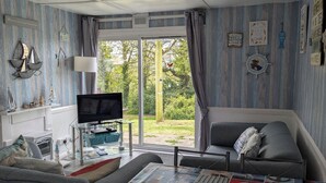 Una sala de estar acogedora con un sofá, una mesa de centro con revistas, un televisor y una ventana con cortinas.