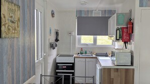 Una cocina compacta con comedor, que incluye una mesa con mantel de temática náutica, un horno pequeño, un microondas y un lavabo.