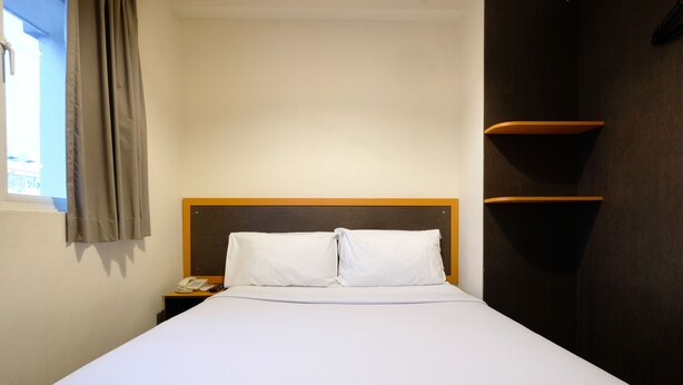 A hotel room with a single bed, a nightstand with a telephone, and a window with curtains. - Kim Tian Hotel Star (Singapore)