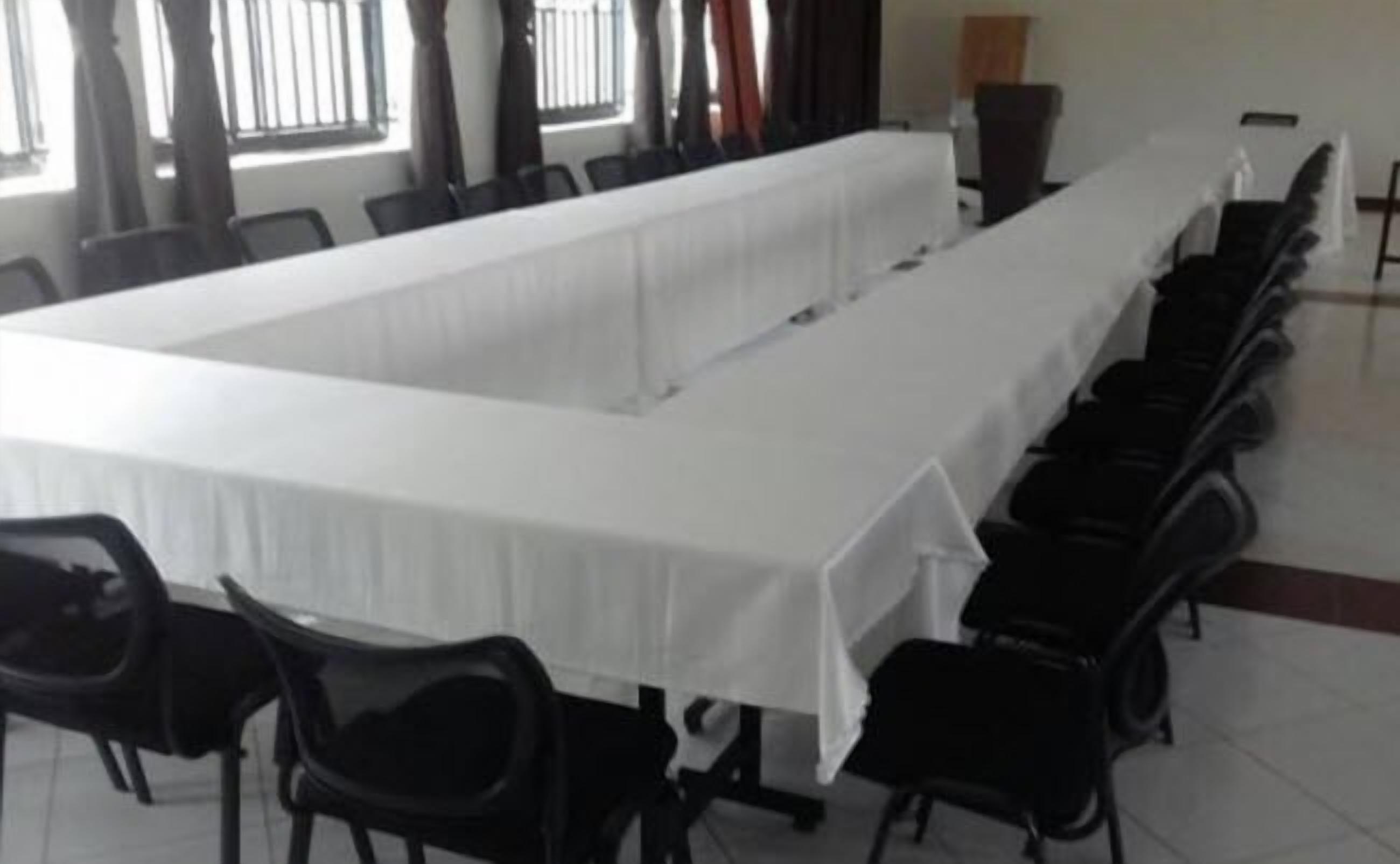 A conference room with a long table and rows of chairs.