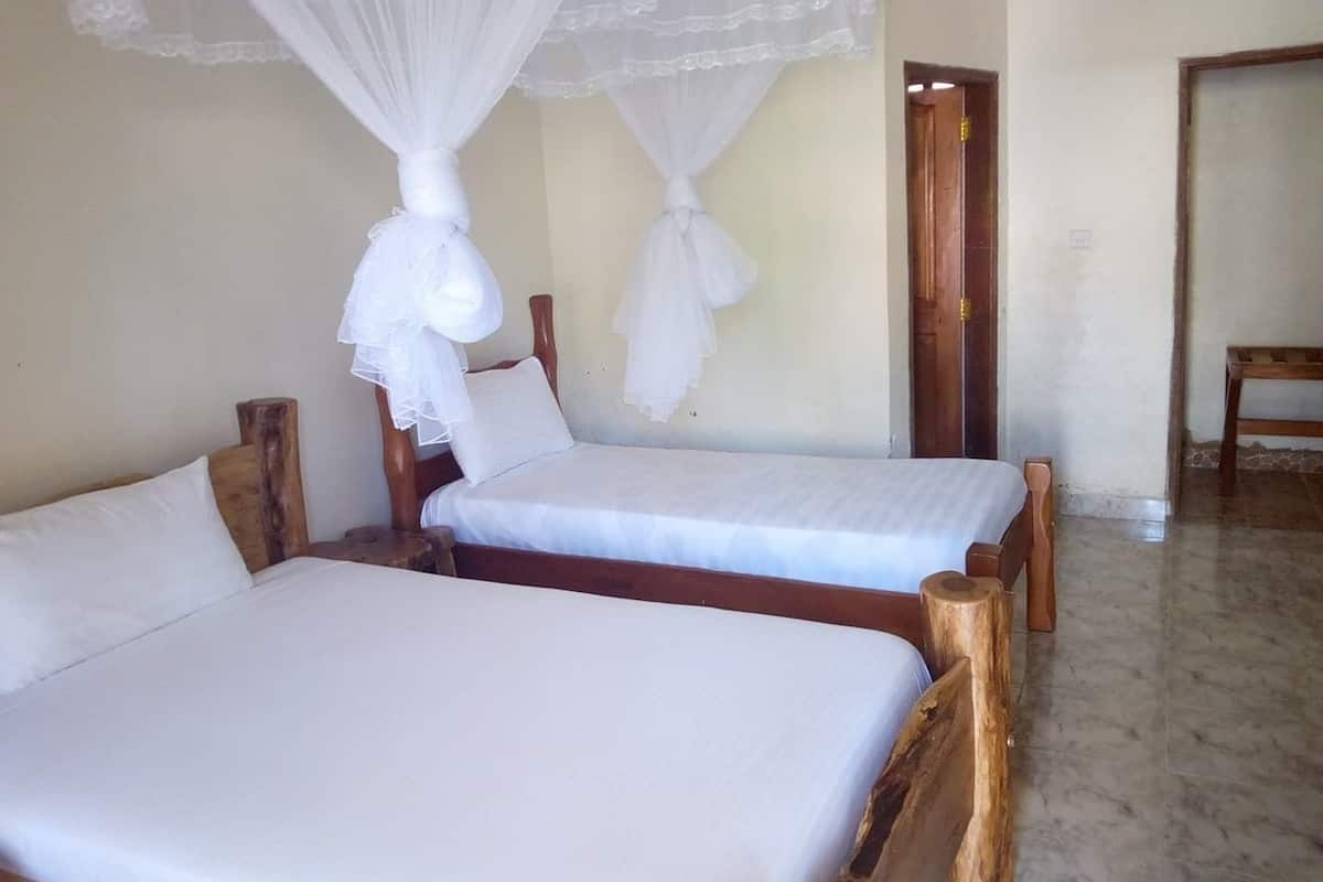 Two wooden beds with white linens and mosquito nets.
