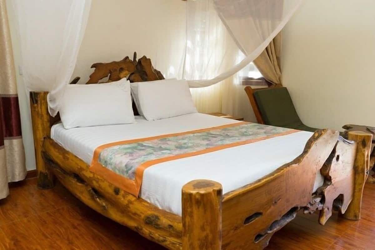 A bed with a wooden frame, white bedding, and a floral-patterned blanket.
