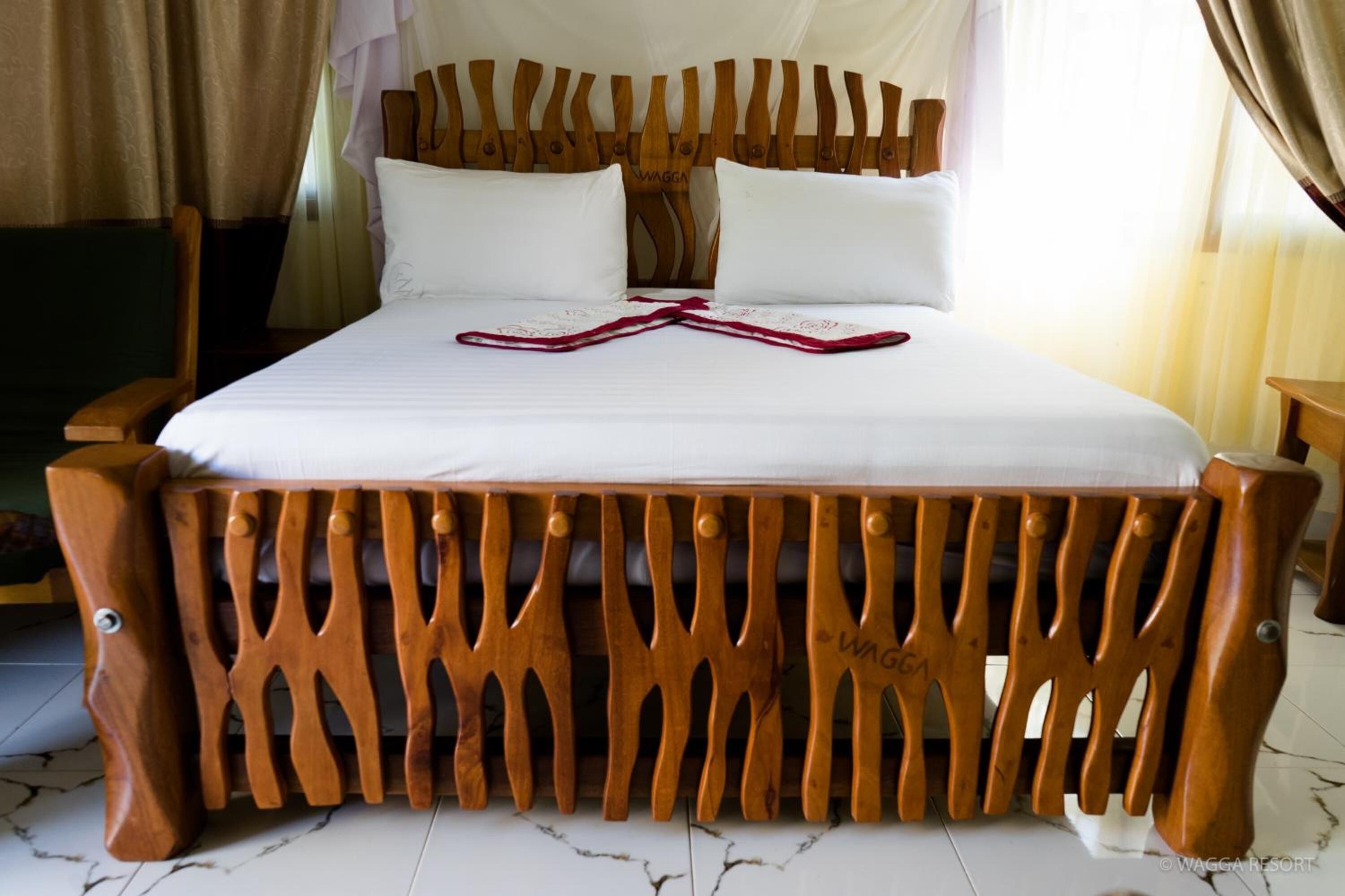 A wooden-framed bed with white linens and a decorative headboard.