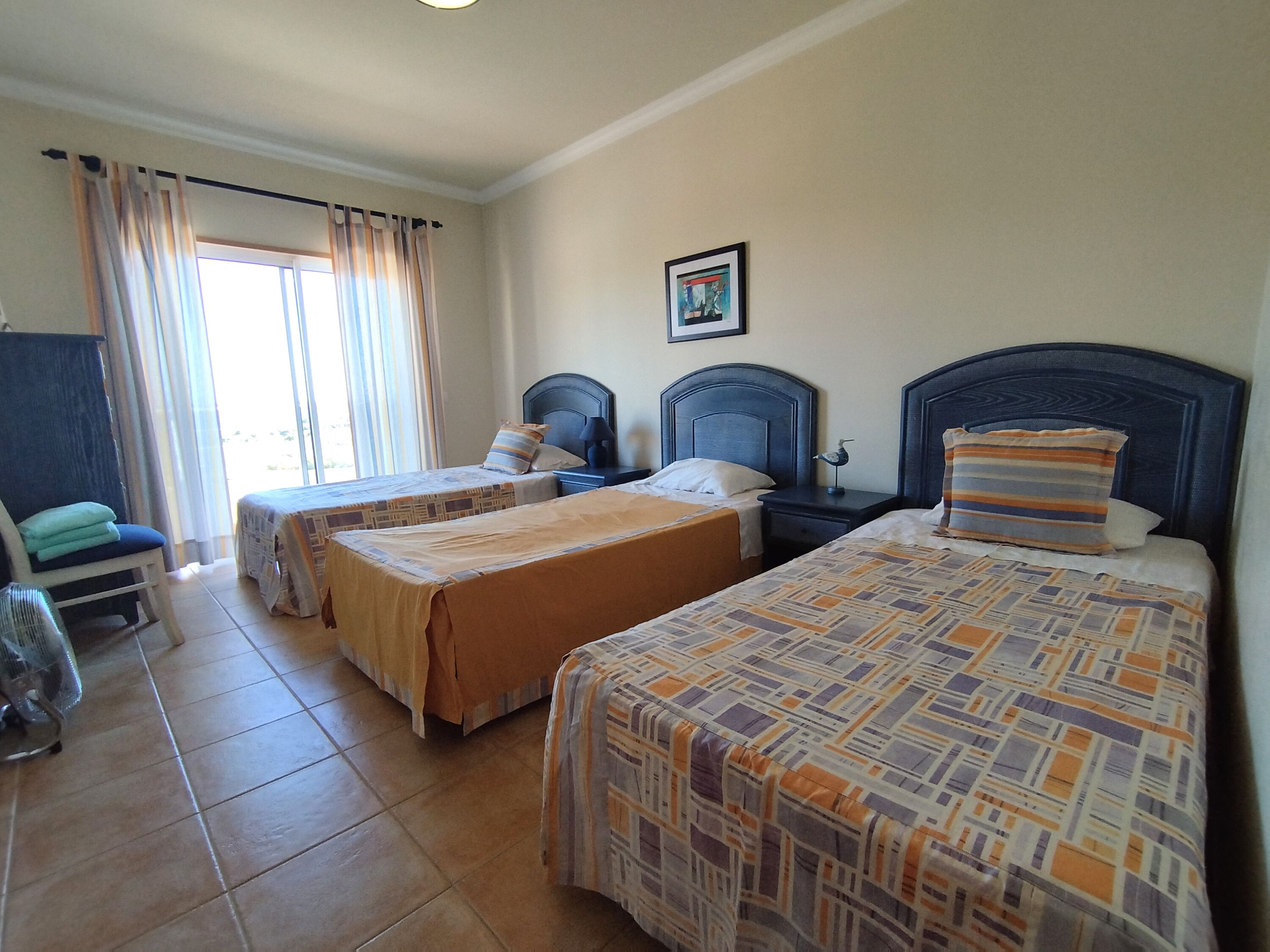 Une chambre d’hôtel avec deux lits, une chaise, une petite table et une fenêtre avec des rideaux.