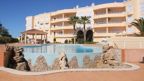 Un hotel con piscina, varios balcones y una zona cubierta.
