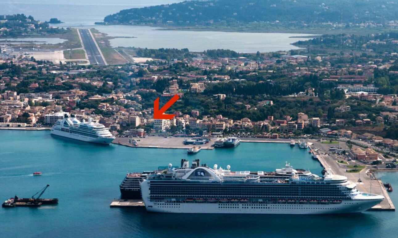 A large cruise ship docked at a port with a cityscape in the background.