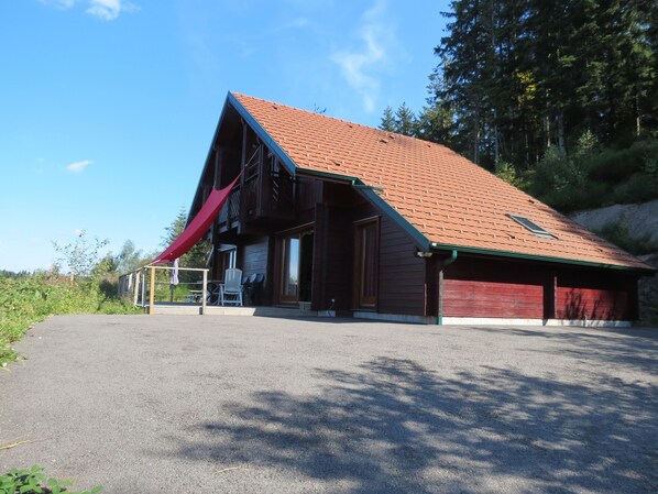 Een houten gebouw met een schuin dak en een rode luifel, met een overdekt terras.