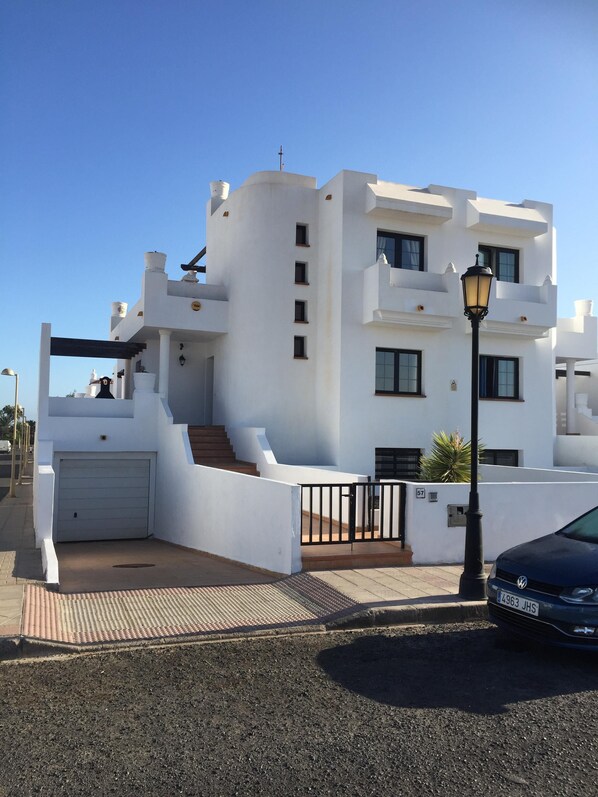 A white building with a garage, a staircase, and a street lamp.