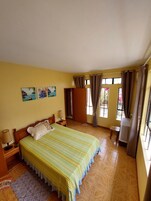 Un dormitorio con una cama grande, una mesita de noche, una lámpara, un armario de madera y una ventana con cortinas.