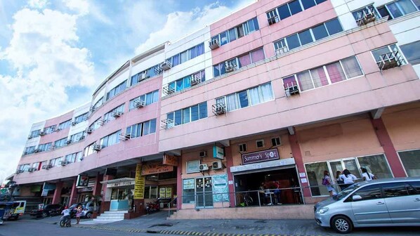 Un edificio de varios pisos con varios comercios en la planta baja, incluyendo un restaurante visible llamado "Summer's Spot".