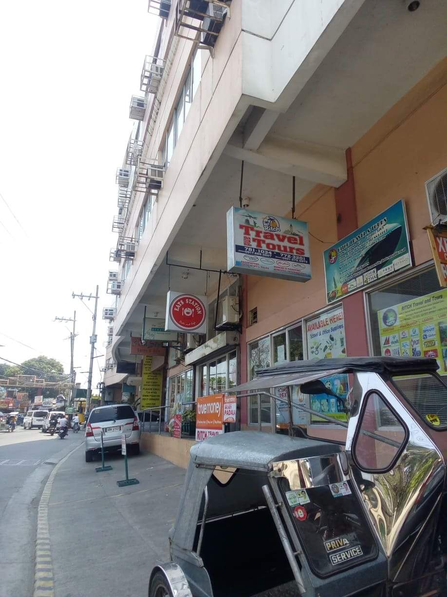 Una vista di strada con un edificio che presenta diversi cartelli, tra cui un'agenzia di viaggi e un ristorante.