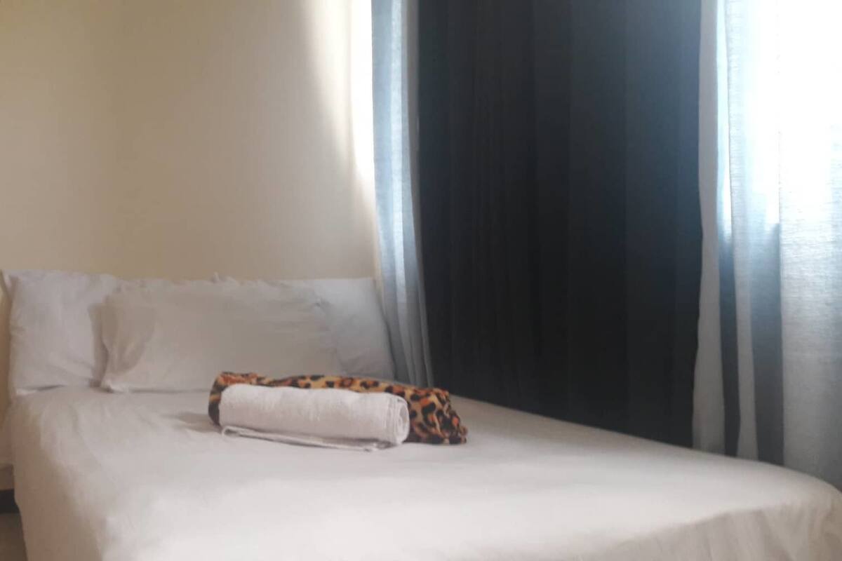 Una cama con sábanas blancas y un cojín estampado de leopardo.