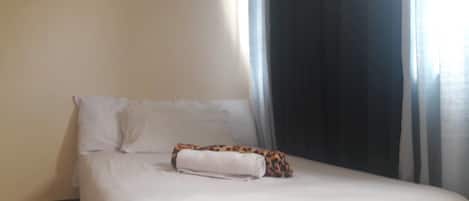 A bed with white linens and a leopard print pillow.