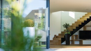 Un intérieur moderne avec un escalier, un téléviseur à écran plat et une porte en verre donnant sur un espace extérieur.