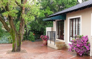 A traditional building with a tiled roof, a brick pathway, and lush greenery. - 174 Premier Guesthouse (Pretoria)