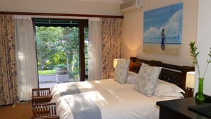 Habitación de hotel con una cama grande, cabecero de madera y vistas a zonas verdes.