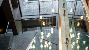 A modern staircase with glass railings and hanging pendant lights.